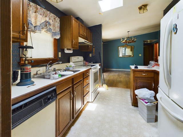 kitchen with white appliances, pendant lighting, vaulted ceiling with skylight, sink, and a baseboard heating unit