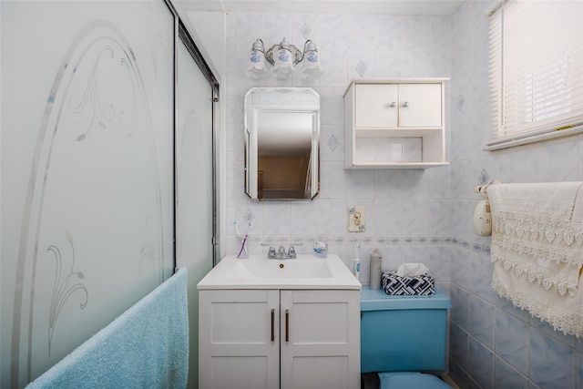 bathroom with vanity, a shower with door, and tile walls