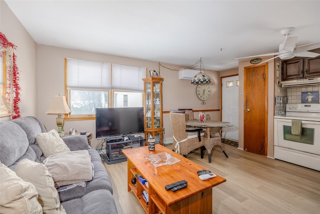 living room with a wall mounted AC, ceiling fan, and light hardwood / wood-style flooring