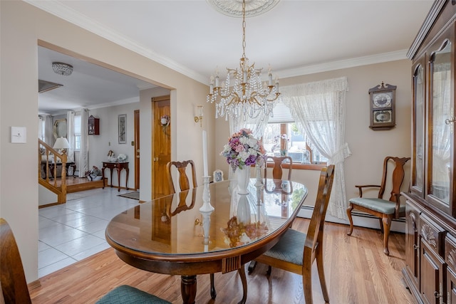 dining area with a notable chandelier, ornamental molding, and light hardwood / wood-style floors