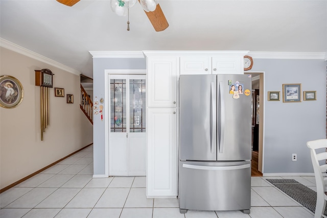 kitchen with light tile patterned flooring, ornamental molding, stainless steel fridge, and white cabinets