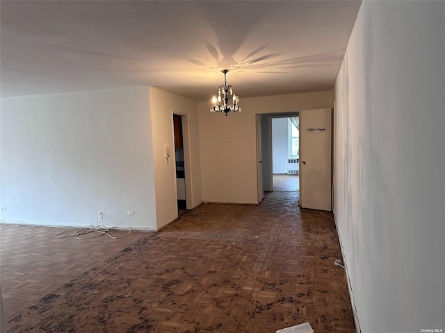 spare room with dark parquet flooring and a notable chandelier