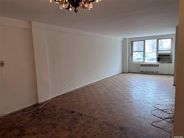 unfurnished room featuring cooling unit, an inviting chandelier, parquet flooring, and radiator