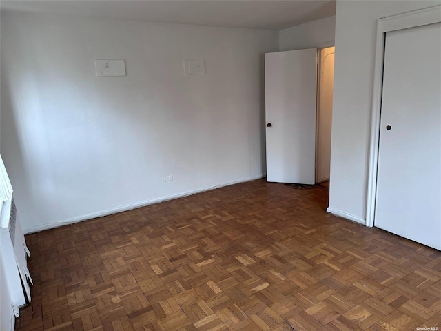 unfurnished bedroom featuring dark parquet flooring