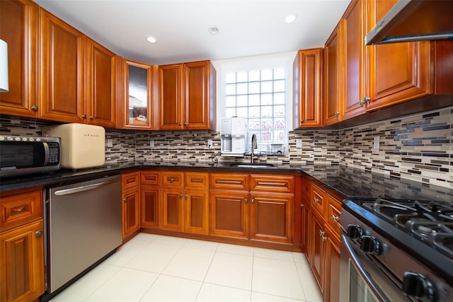 kitchen featuring appliances with stainless steel finishes, light tile patterned floors, decorative backsplash, and sink