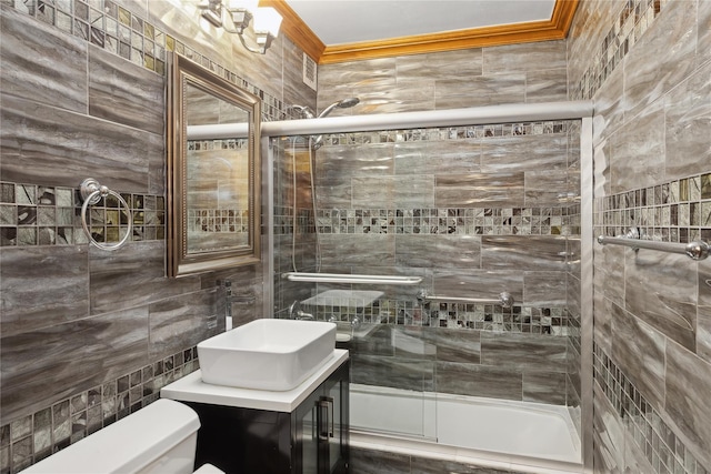 full bathroom featuring toilet, vanity, tile walls, ornamental molding, and shower / bath combination with glass door