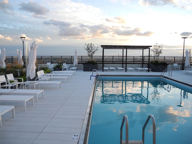 pool at dusk featuring a patio area