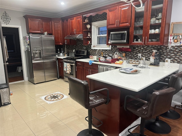 kitchen with kitchen peninsula, appliances with stainless steel finishes, light tile patterned flooring, and a breakfast bar area