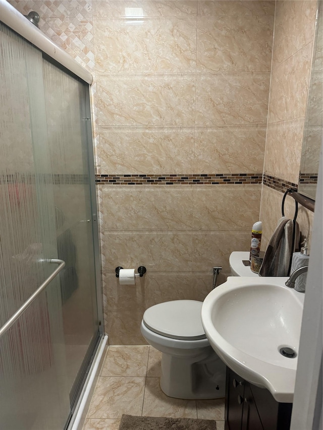 bathroom with toilet, tile patterned flooring, tile walls, a shower with door, and vanity