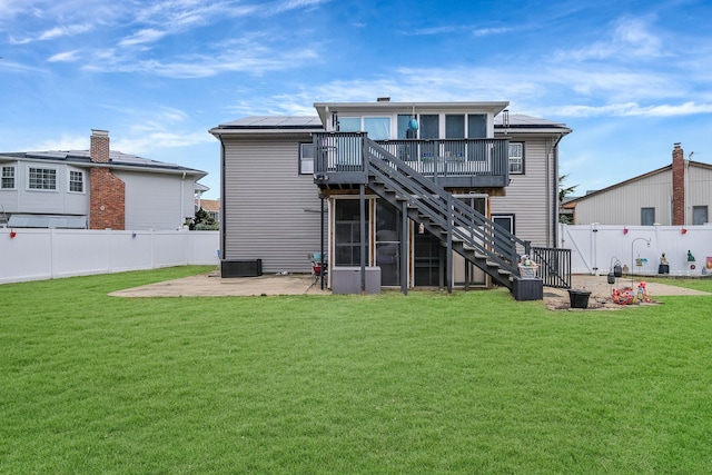 back of property with a lawn, a wooden deck, a patio, and a sunroom