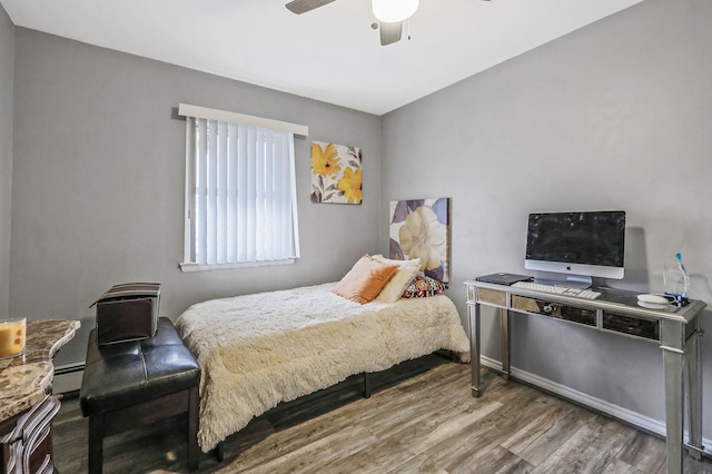 bedroom featuring ceiling fan, baseboard heating, and wood-type flooring