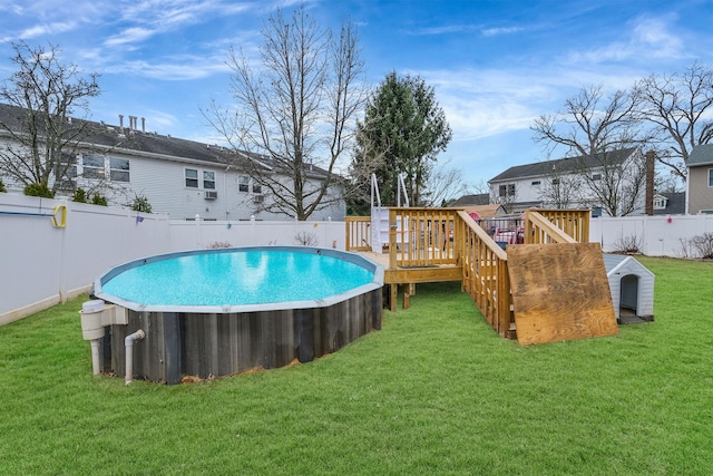 view of swimming pool featuring a lawn and a deck