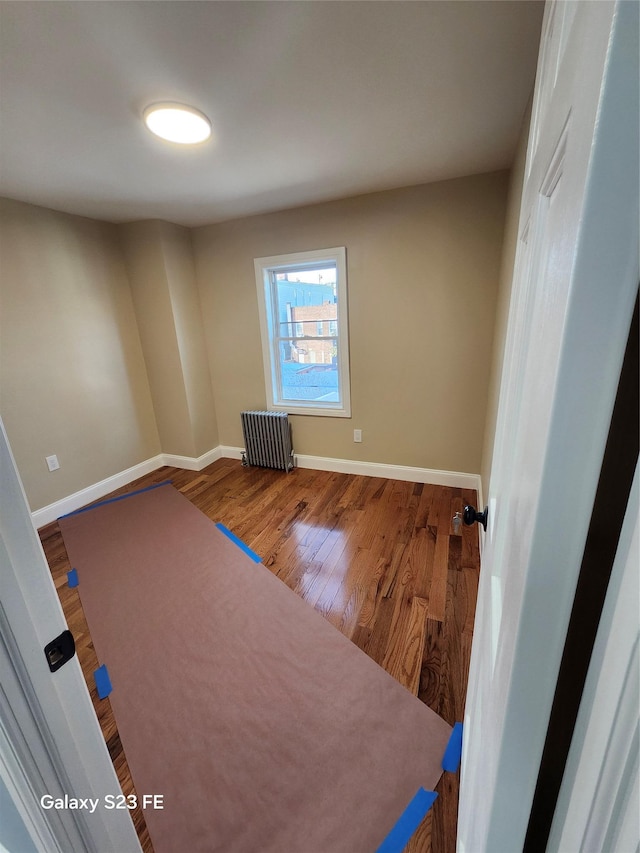 unfurnished room with wood-type flooring and radiator