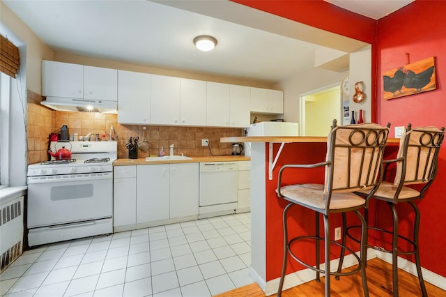 kitchen with sink, white cabinets, white appliances, decorative backsplash, and a breakfast bar