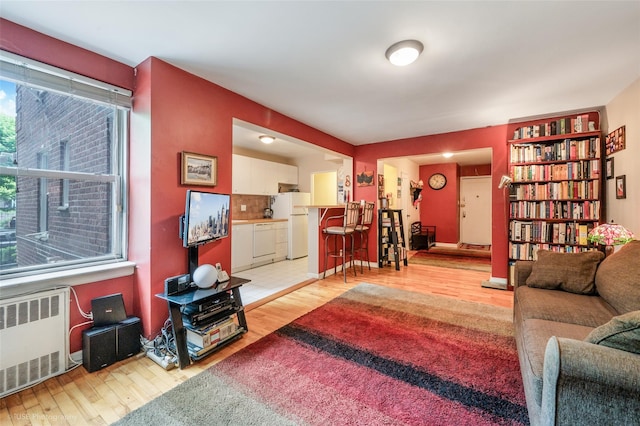 living room with a wealth of natural light, wood-type flooring, and radiator heating unit