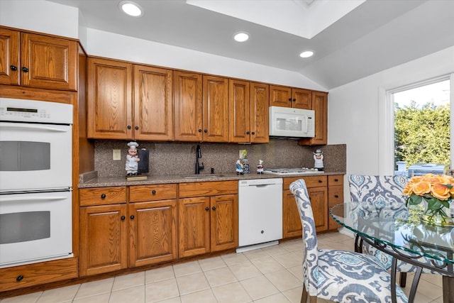 kitchen with lofted ceiling with skylight, sink, decorative backsplash, light tile patterned floors, and white appliances