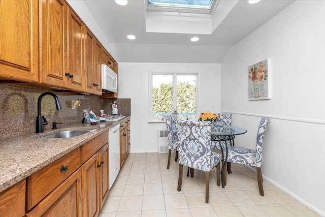 kitchen featuring sink, white appliances, radiator, tasteful backsplash, and light stone countertops