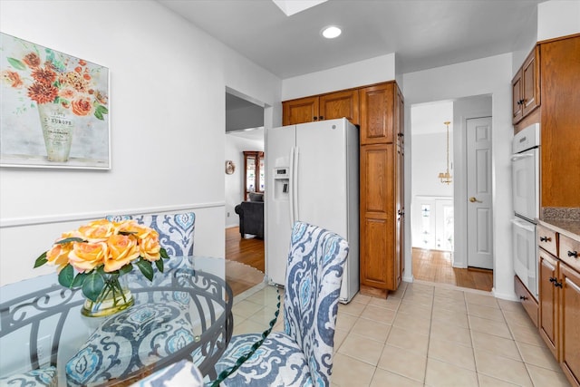 kitchen with light tile patterned floors, white appliances, and a skylight