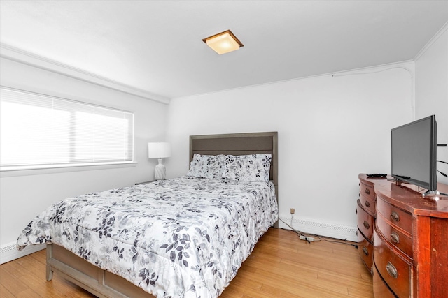 bedroom featuring crown molding, light hardwood / wood-style floors, and a baseboard heating unit