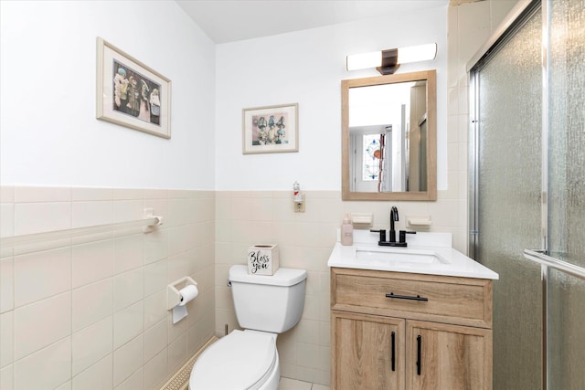 bathroom with vanity, toilet, an enclosed shower, and tile walls