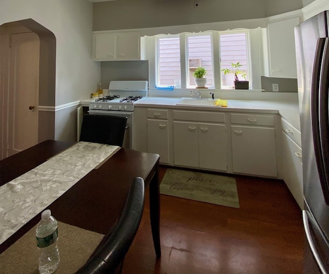 kitchen featuring stainless steel fridge, dark hardwood / wood-style flooring, sink, white cabinets, and white gas stove