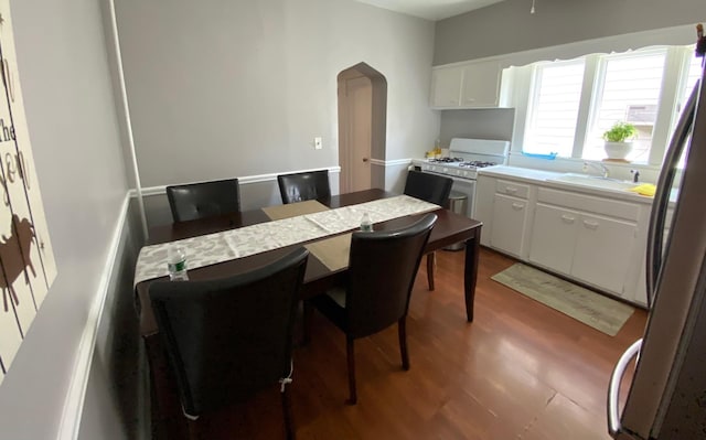 kitchen featuring white gas stove, stainless steel refrigerator, a kitchen breakfast bar, white cabinets, and sink