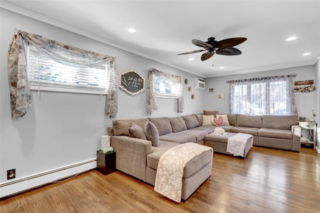 living room featuring baseboard heating, ornamental molding, wood-type flooring, and ceiling fan