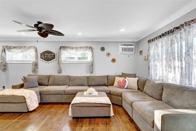 living room with ceiling fan, hardwood / wood-style floors, an AC wall unit, and a healthy amount of sunlight