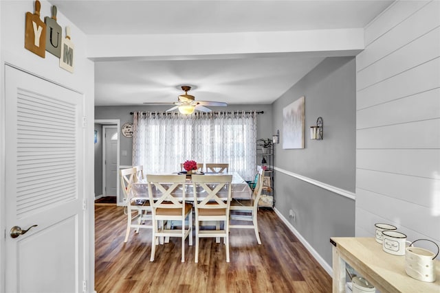 dining room featuring ceiling fan, wooden walls, and hardwood / wood-style flooring