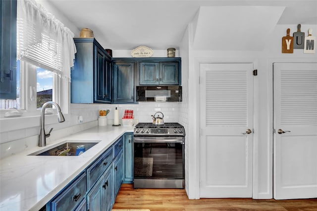 kitchen with gas range, blue cabinets, light hardwood / wood-style floors, and sink