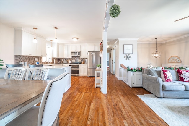 dining space featuring sink, light hardwood / wood-style flooring, and crown molding