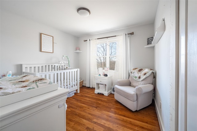 bedroom with a crib and dark hardwood / wood-style floors