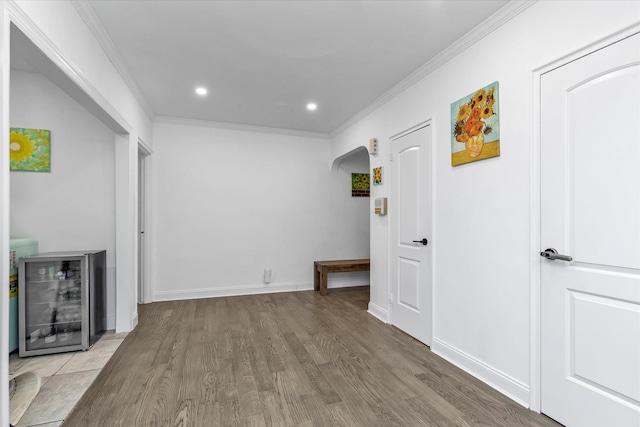 hallway featuring wine cooler, crown molding, and light hardwood / wood-style flooring