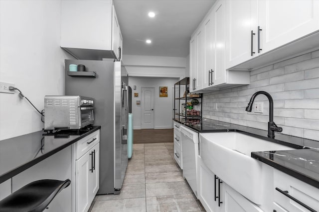 kitchen with white dishwasher, sink, white cabinets, and tasteful backsplash