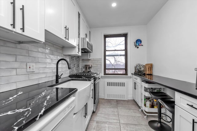 kitchen with white cabinets, radiator heating unit, ventilation hood, gas range, and light tile patterned floors