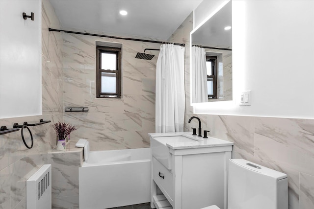 full bathroom featuring toilet, shower / tub combo with curtain, tile walls, vanity, and radiator heating unit