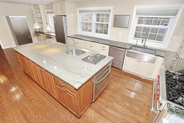 kitchen featuring stainless steel appliances, a kitchen island, stone countertops, backsplash, and sink