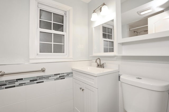 bathroom with toilet, vanity, and tile walls