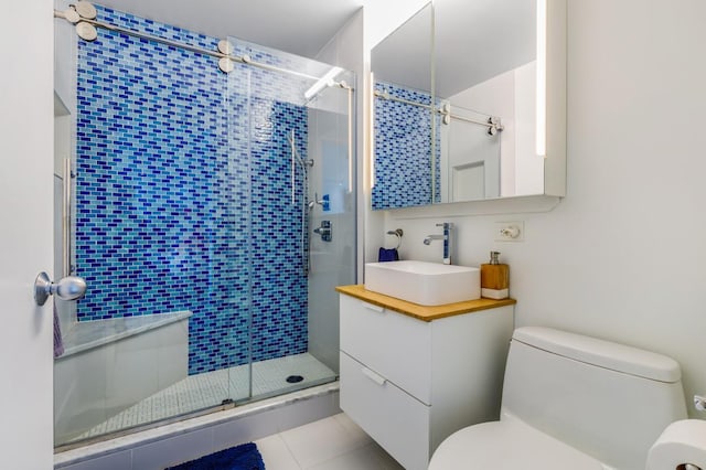 bathroom featuring toilet, tile patterned flooring, a shower with shower door, and vanity