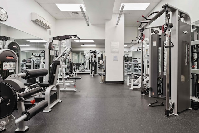 exercise room featuring a paneled ceiling and a wall unit AC