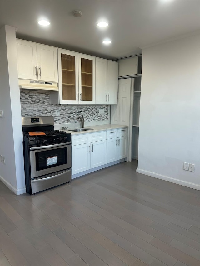 kitchen featuring hardwood / wood-style floors, stainless steel gas stove, backsplash, white cabinetry, and sink