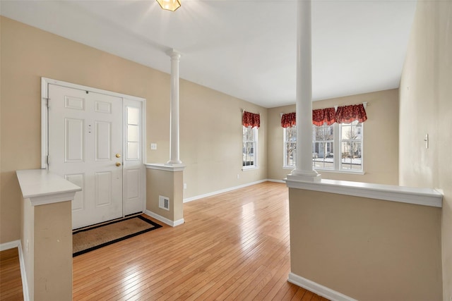 foyer entrance with decorative columns and light wood-type flooring