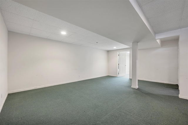 basement featuring dark colored carpet and a paneled ceiling