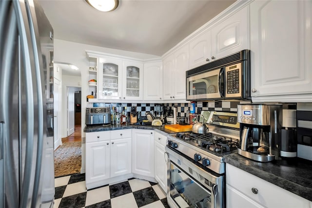 kitchen featuring stainless steel appliances, white cabinets, and backsplash