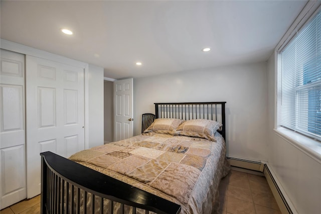 tiled bedroom featuring a closet and a baseboard heating unit