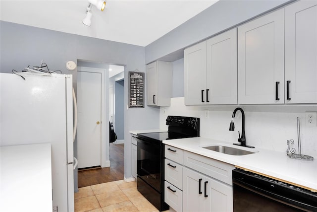 kitchen featuring black appliances, white cabinetry, sink, and light tile patterned floors