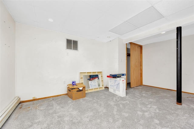 basement featuring a baseboard heating unit and carpet