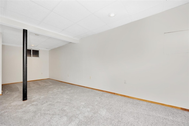 basement featuring a paneled ceiling and light carpet