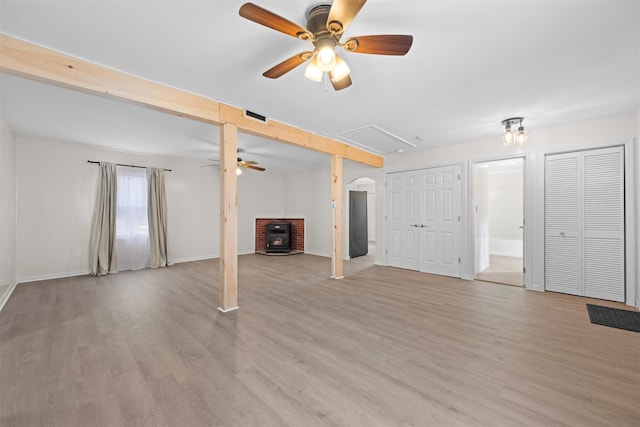 unfurnished living room with light hardwood / wood-style floors, ceiling fan, and a wood stove