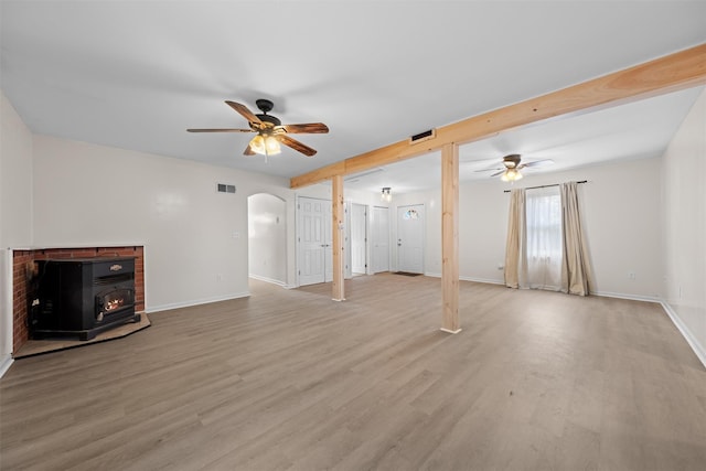 unfurnished living room featuring ceiling fan, light wood-type flooring, and a wood stove